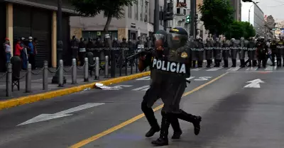Polica se prepara para disparar una bomba lacrimgena a los manifestantes en Li
