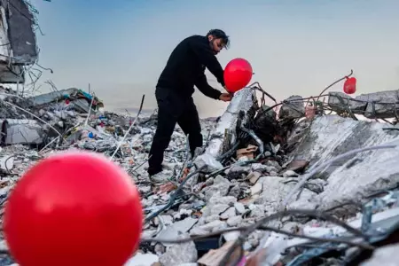 Ogun Sever Okur junto a su asociación atan globos rojos en los escombros del ter