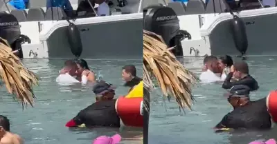 Pareja tiene intimidad en una playa repleta de turistas.