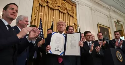 Donald Trump con el documento que cuenta con su firma.