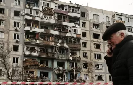 Hombre frente a edificio destruido en Ucrania