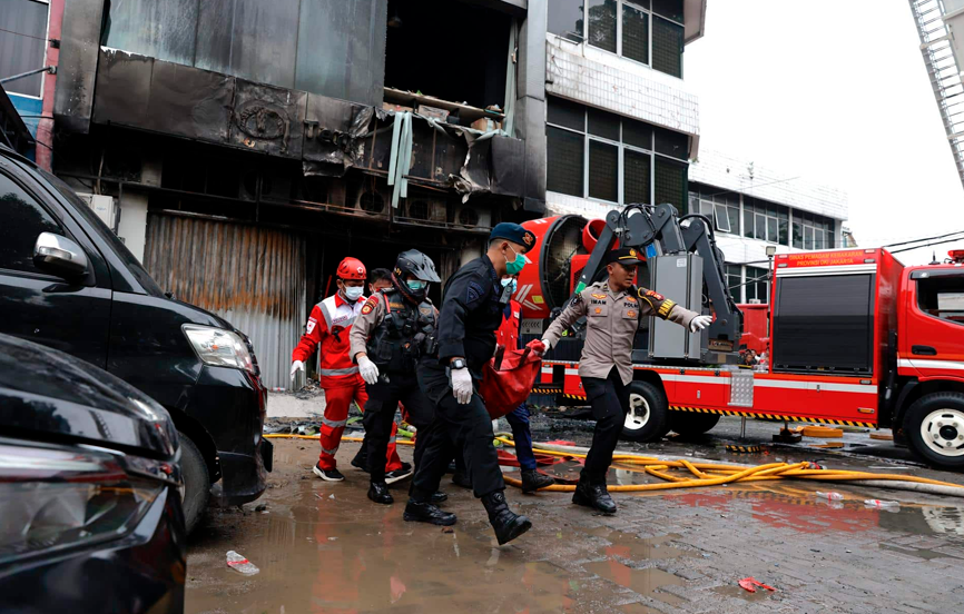 Bomberos y efectivos policiales ayudan a los heridos y personas atrapadas en el incendio en Yakarta.